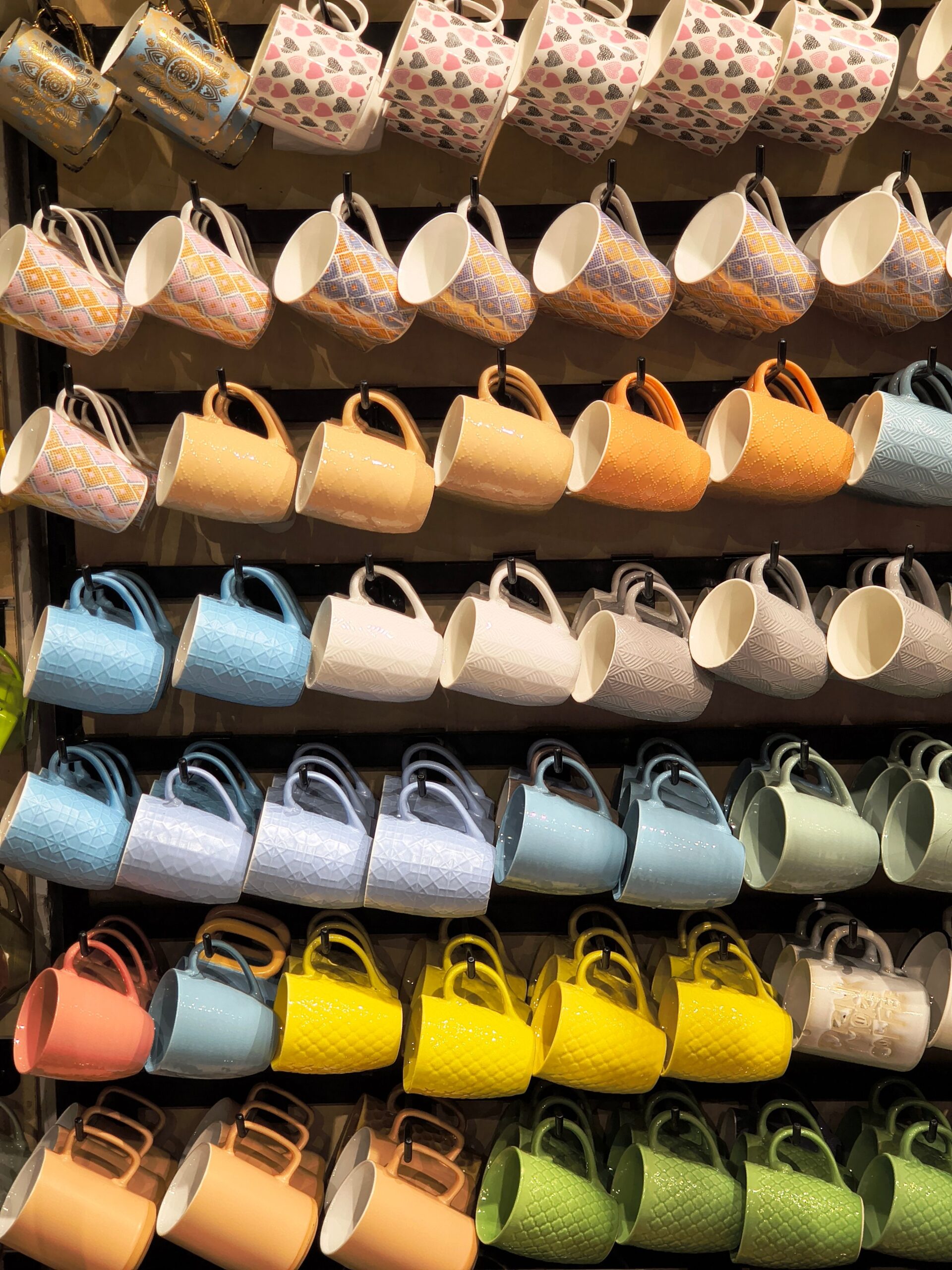 Rows of colorful mugs on store shelves.