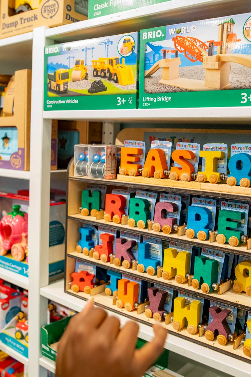 Bright toy store shelves stocked with games and wooden alphabet toys.