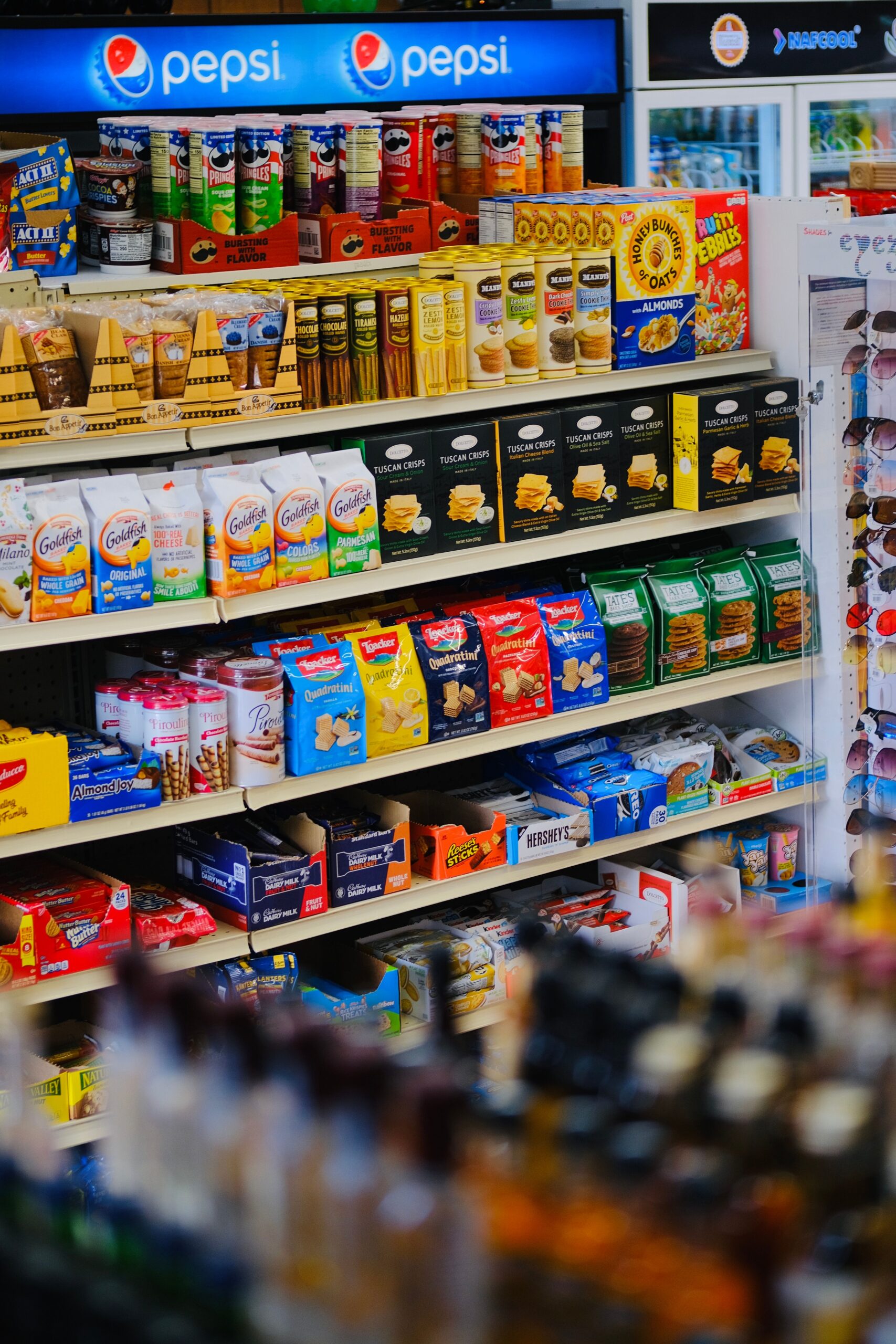 Aisle of colorful packaged snacks in a variety store.